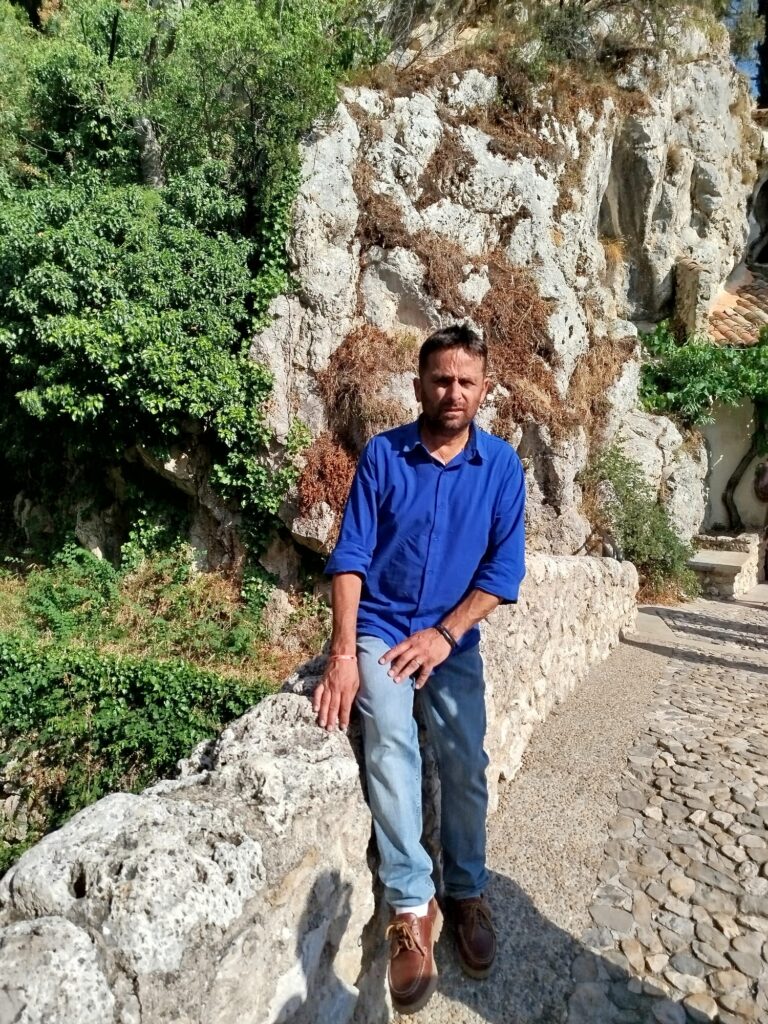 Daryl appuyé sur un muret en pierre à Moustiers-Sainte-Marie, devant les falaises provençales, lors du tournage du clip Enfant de la Provence.