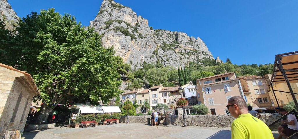Vue panoramique de la place de Moustiers-Sainte-Marie dominée par les falaises calcaires du Verdon, en Provence, lors du tournage du clip Enfant de la Provence de Daryl.